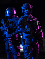 Image showing Modern warfare soldiers in dark with combat ammunition and weapons in the hands of equipped laser sights are in battle order. Mixed media.