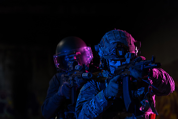 Image showing Modern warfare soldiers in dark with combat ammunition and weapons in the hands of equipped laser sights are in battle order. Mixed media.