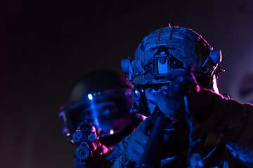 Image showing Modern warfare soldiers in dark with combat ammunition and weapons in the hands of equipped laser sights are in battle order. Mixed media.