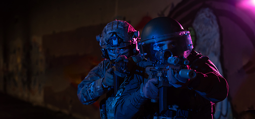 Image showing Modern warfare soldiers in dark with combat ammunition and weapons in the hands of equipped laser sights are in battle order. Mixed media.