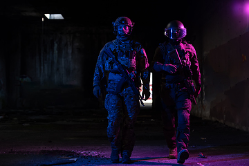 Image showing Modern warfare soldiers in dark with combat ammunition and weapons in the hands of equipped laser sights are in battle order. Mixed media.