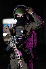 Image showing Army soldier in Combat Uniforms with an assault rifle and combat helmet night mission dark background. Blue and purple gel light effect.