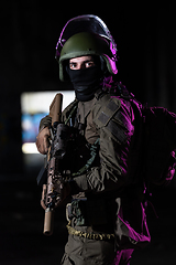 Image showing Army soldier in Combat Uniforms with an assault rifle and combat helmet night mission dark background. Blue and purple gel light effect.