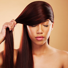 Image showing Hair care, shine and a young woman in studio for salon, hairdresser and wellness results. Strong texture, cosmetics and shampoo for repair or growth for aesthetic model person on a brown background