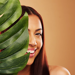 Image showing Leaf, beauty and portrait of a happy woman in studio for natural dermatology, cosmetics or wellness. Skin care, nature and monstera plant for eco friendly facial of model person on brown background