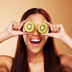Image showing Beauty, kiwi and a woman with skin care in studio for natural dermatology, cosmetics or glow. Facial, fruit and healthy diet for vitamin c and nutrition of excited model person on a brown background