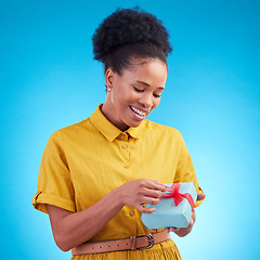 Image showing Happy, gift and a black woman in studio with a surprise for birthday, celebration or holiday. Fashion, present and african female person on a blue background with a box, ribbon and prize or package