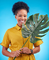 Image showing Fashion, portrait and black woman with plant on blue background for eco friendly, organic and natural clothes. Nature, happy and female person with monstera leaf for sustainable clothing in studio