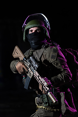 Image showing Army soldier in Combat Uniforms with an assault rifle and combat helmet night mission dark background. Blue and purple gel light effect.