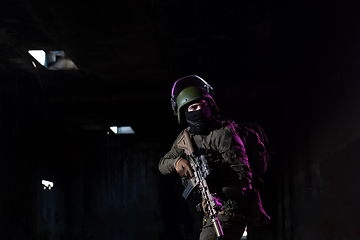Image showing Army soldier in Combat Uniforms with an assault rifle and combat helmet night mission dark background. Blue and purple gel light effect.