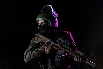 Image showing Army soldier in Combat Uniforms with an assault rifle and combat helmet night mission dark background. Blue and purple gel light effect.