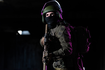 Image showing Army soldier in Combat Uniforms with an assault rifle and combat helmet night mission dark background. Blue and purple gel light effect.