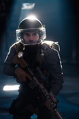 Image showing Army soldier in Combat Uniforms with an assault rifle and combat helmet night mission dark background. Blue and purple gel light effect.