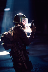 Image showing Army soldier in Combat Uniforms with an assault rifle and combat helmet night mission dark background. Blue and purple gel light effect.