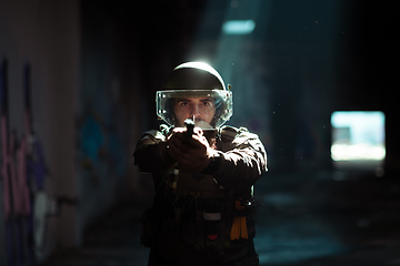 Image showing Soldier of army elite forces, special security service fighter with hidden behind mask and glasses face, in helmet and load carriage system, aiming with service pistol low key.