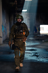 Image showing Army soldier in Combat Uniforms with an assault rifle and combat helmet night mission dark background. Blue and purple gel light effect.