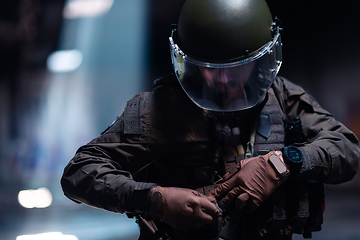 Image showing Army soldier in Combat Uniforms with an assault rifle and combat helmet night mission dark background. Blue and purple gel light effect.