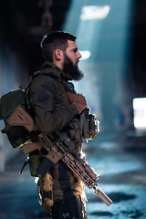 Image showing Army soldier in Combat Uniforms with an assault rifle and combat helmet night mission dark background. Blue and purple gel light effect.