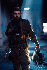 Image showing Army soldier in Combat Uniforms with an assault rifle and combat helmet night mission dark background. Blue and purple gel light effect.