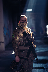 Image showing Army soldier in Combat Uniforms with an assault rifle and combat helmet night mission dark background. Blue and purple gel light effect.