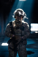 Image showing Army soldier in Combat Uniforms with an assault rifle and combat helmet night mission dark background. Blue and purple gel light effect.