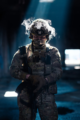 Image showing Army soldier in Combat Uniforms with an assault rifle and combat helmet night mission dark background. Blue and purple gel light effect.