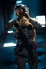 Image showing Army soldier in Combat Uniforms with an assault rifle and combat helmet night mission dark background. Blue and purple gel light effect.