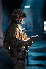 Image showing Soldier of army elite forces, special security service fighter with hidden behind mask and glasses face, in helmet and load carriage system, aiming with service pistol low key.