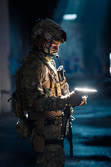 Image showing A special forces soldier reloads his pistol as he prepares for a military operation