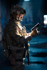 Image showing A special forces soldier reloads his pistol as he prepares for a military operation