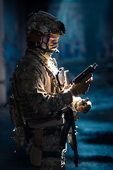 Image showing Soldier of army elite forces, special security service fighter with hidden behind mask and glasses face, in helmet and load carriage system, aiming with service pistol low key.