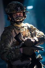 Image showing Soldier of army elite forces, special security service fighter with hidden behind mask and glasses face, in helmet and load carriage system, aiming with service pistol low key.