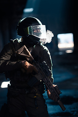 Image showing Army soldier in Combat Uniforms with an assault rifle and combat helmet night mission dark background. Blue and purple gel light effect.