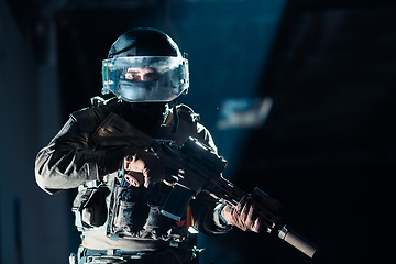 Image showing Army soldier in Combat Uniforms with an assault rifle and combat helmet night mission dark background. Blue and purple gel light effect.