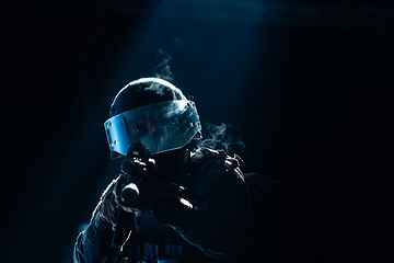 Image showing Army soldier in Combat Uniforms with an assault rifle and combat helmet night mission dark background. Blue and purple gel light effect.