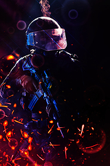 Image showing Army soldier in Combat Uniforms with an assault rifle and combat helmet night mission dark background. Blue and purple gel light effect.