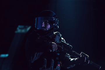 Image showing Army soldier in Combat Uniforms with an assault rifle and combat helmet night mission dark background. Blue and purple gel light effect.