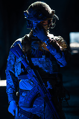 Image showing Army soldier in Combat Uniforms with an assault rifle and combat helmet night mission dark background. Blue and purple gel light effect.