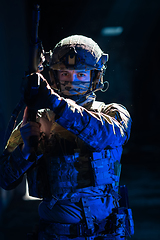 Image showing Army soldier in Combat Uniforms with an assault rifle and combat helmet night mission dark background. Blue and purple gel light effect.