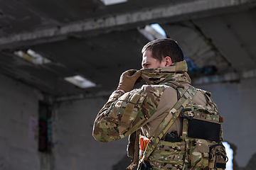 Image showing Army soldier in Combat Uniforms with an assault rifle and face protection mask.