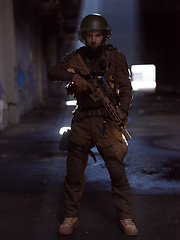 Image showing Army soldier in Combat Uniforms with an assault rifle and combat helmet night mission dark background. Blue and purple gel light effect.