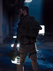 Image showing Army soldier in Combat Uniforms with an assault rifle and combat helmet night mission dark background. Blue and purple gel light effect.