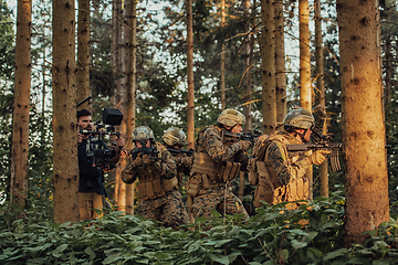 Image showing Videographer with Professional Movie Video Camera Gimbal Stabilizing Equipment Taking Action Shoot of Soldiers in Action in Forest