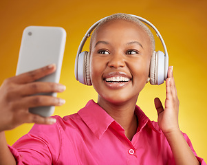 Image showing Selfie, smile and black woman with music headphones in studio, streaming or subscription on yellow background. Podcast, profile picture and lady social media influencer online for radio or blog post