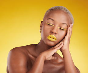 Image showing Face, creative makeup and lipstick with a black woman in studio on a yellow background for beauty, art or cosmetics. Gold, color and eyeshadow on young model with eyes closed and unique aesthetic