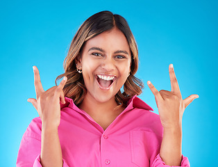 Image showing Happy, portrait and woman with rocker hands in studio for freedom, fun and positive attitude on blue background. smile, face and female with rockstar emoji, sign or punk gesture, good mood or vibes