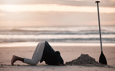 Image showing Digging hole, search and a man on the beach for a vacation, treasure hunt or check underground. Nature, travel and a person with a shovel at the ocean during sunset or sunrise and playing in the sand