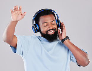 Image showing Headphones, dance and man in a studio with music, playlist or album with a calm mindset. Happy, smile and young African male model streaming a song or radio online isolated by a gray background.