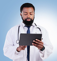 Image showing Healthcare, tablet and a black man doctor in studio on a blue background for cardiology research. Medical, technology and innovation with a male medicine professional searching for information online