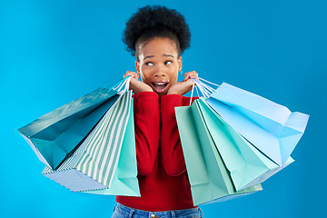 Image showing African woman, shopping bag or thinking in studio with wow, discount or sale by blue background. Gen z girl, student and shock with retail addiction, doubt or ideas for commercial customer experience